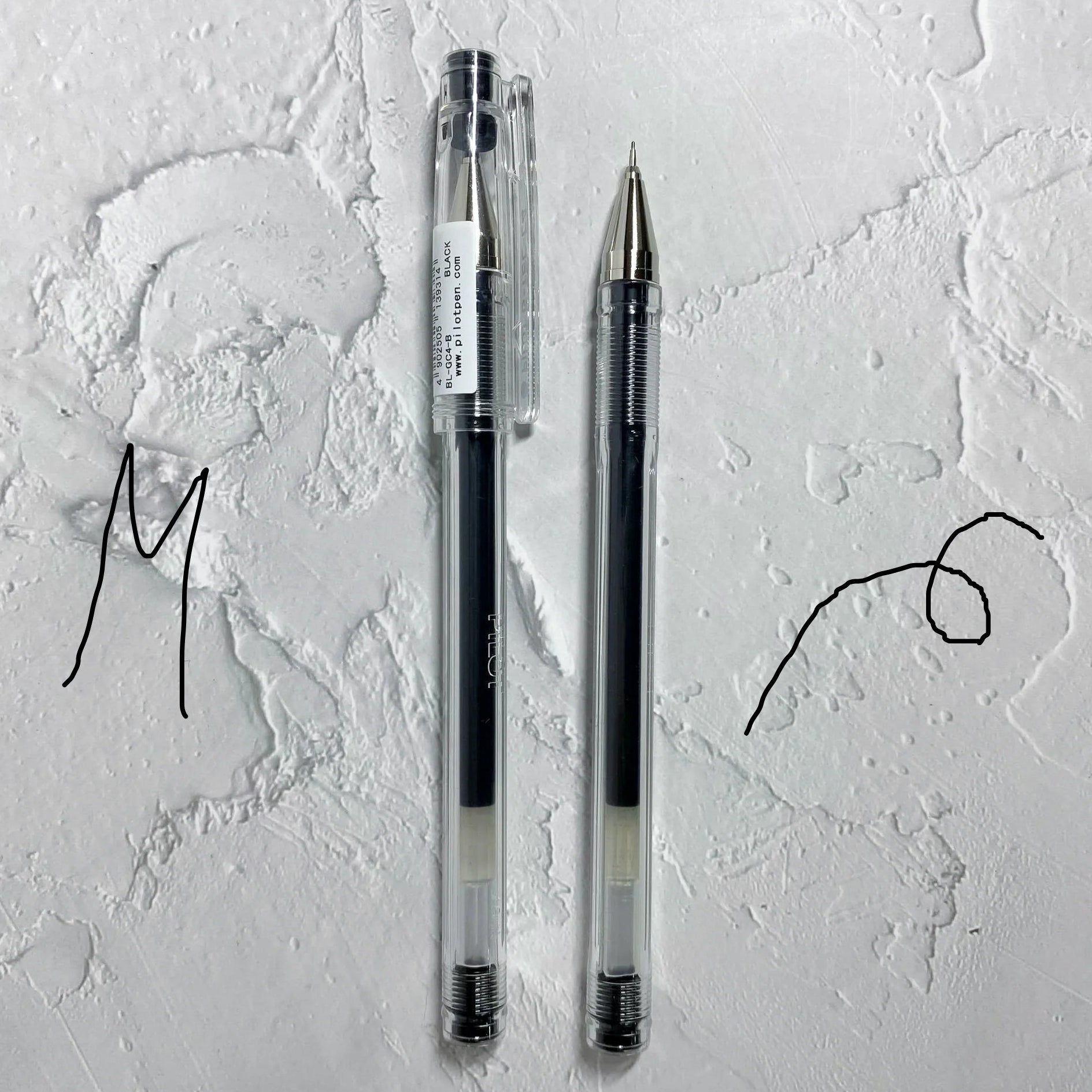 Two pens on a textured white surface with artistic lines.