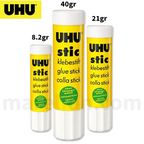 Three UHU glue sticks of different sizes on a white background