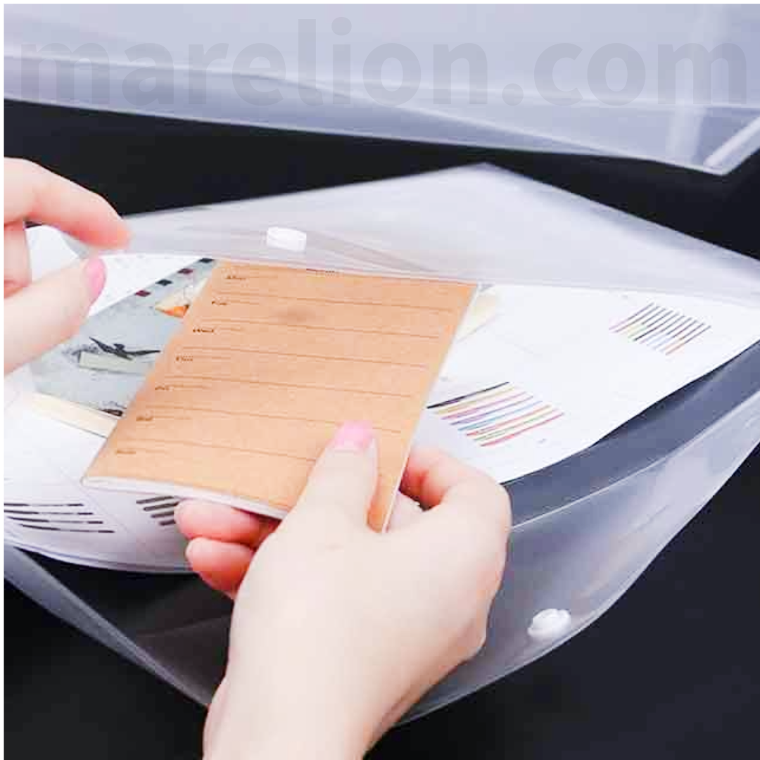 Person holding a small notebook over a clear plastic sheet with printed designs.