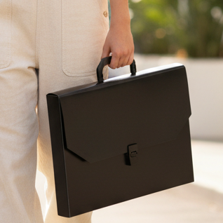 Woman in beige overalls holding a black briefcase walking outdoors.