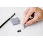 Hand holding a small black object with a white background