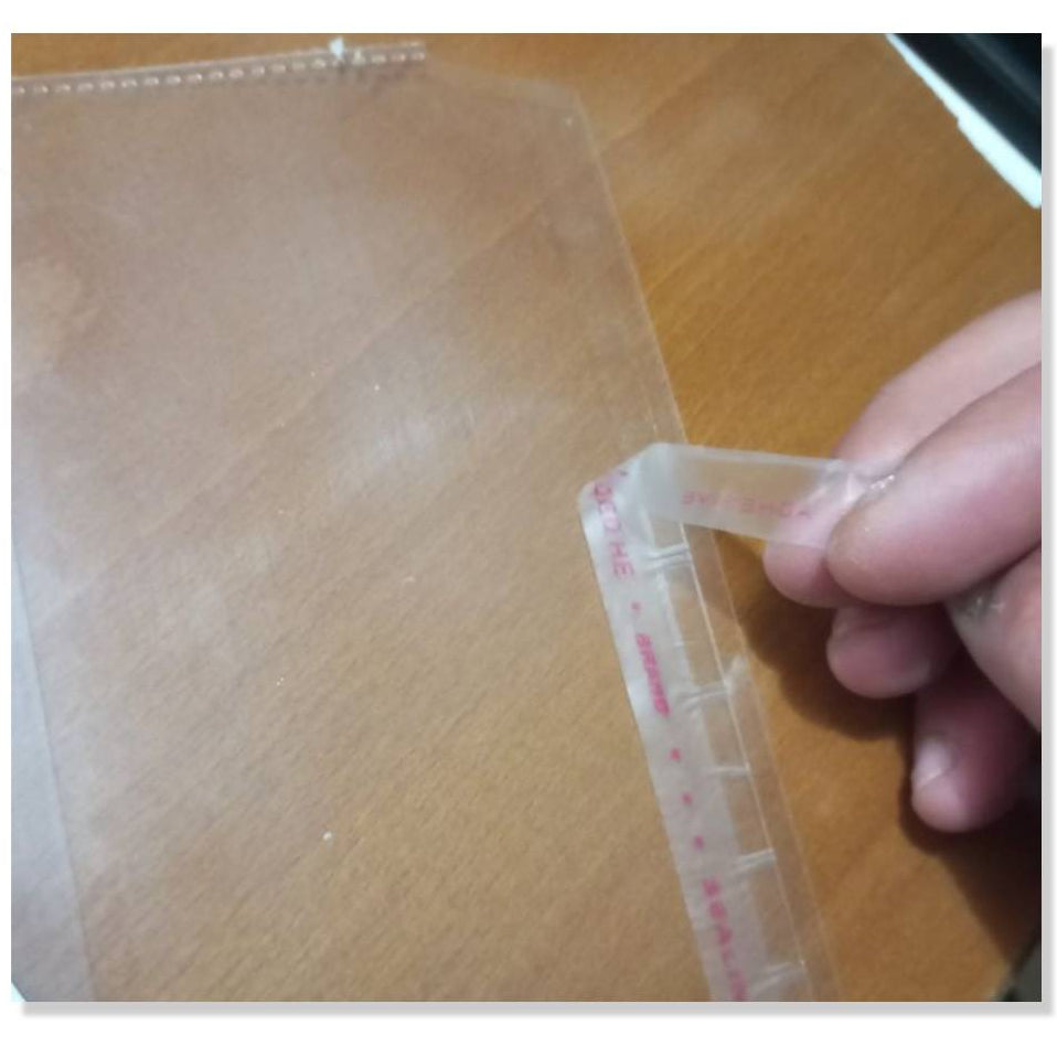 Hand holding a transparent measuring tool with red markings on a wooden surface